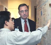 Motorola executive Charlie Backof listens to UCSD grad student describe his research poster