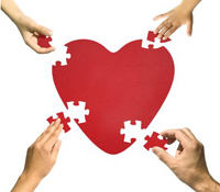 Four hands putting pieces of heart puzzle together