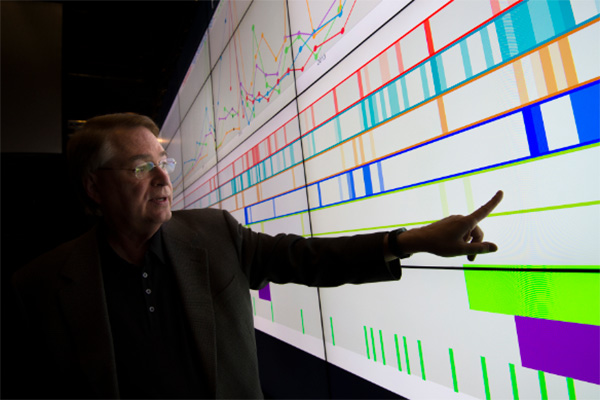 Larry Smarr points to health data on the Vroom visualization wall in the Qualcomm Institute.