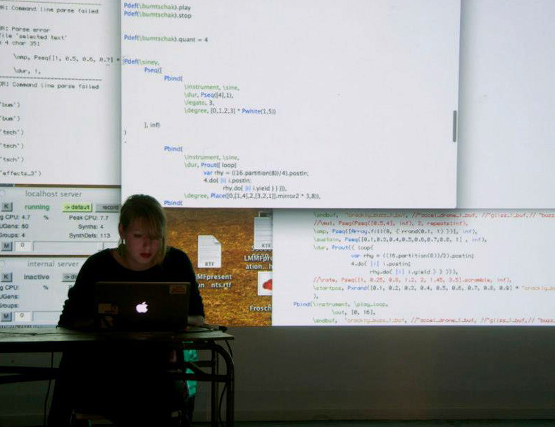Shelly Knotts typing on computer with code displayed behind her