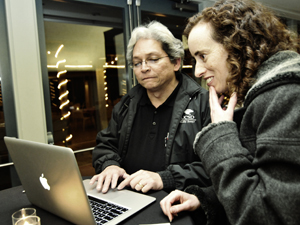 Two people collaborating while looking at a laptop.