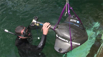 A representative of the Navy assists the iBotics team as the Stingray is lowered into the water at The Space and Naval Warfare System Center's TRANSDEC facility.