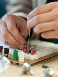 Hands building a guitar pedal with circuits