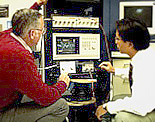 Dr. Robert Scholtz (left) and Moe Win (right) review the signal from the impulse radio on an oscilli